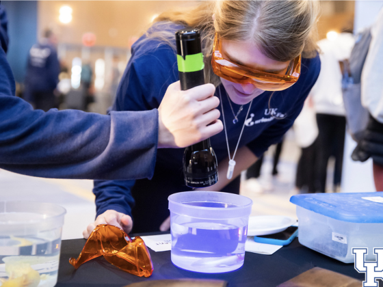 girl looks into container of water
